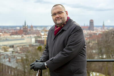 Piotr Lorens stoi na Górze Gradowej, w tle panorama Gdańska