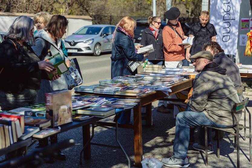 stoły z książkami na ulicy, przy nich sprzedawca i kupujący