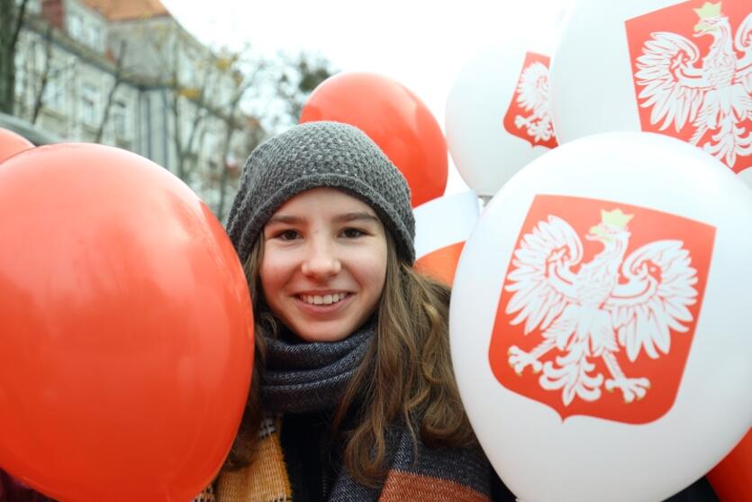 Uśmiechnięta dziewczyna z biało-czerwonymi balonami