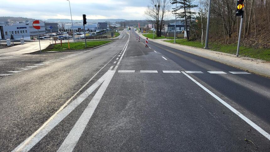 Widok szerokiej nowej asfaltowej drogi z chodnikiem dla pieszych po prawej stronie i pasem wydzielonym dla po lewej 