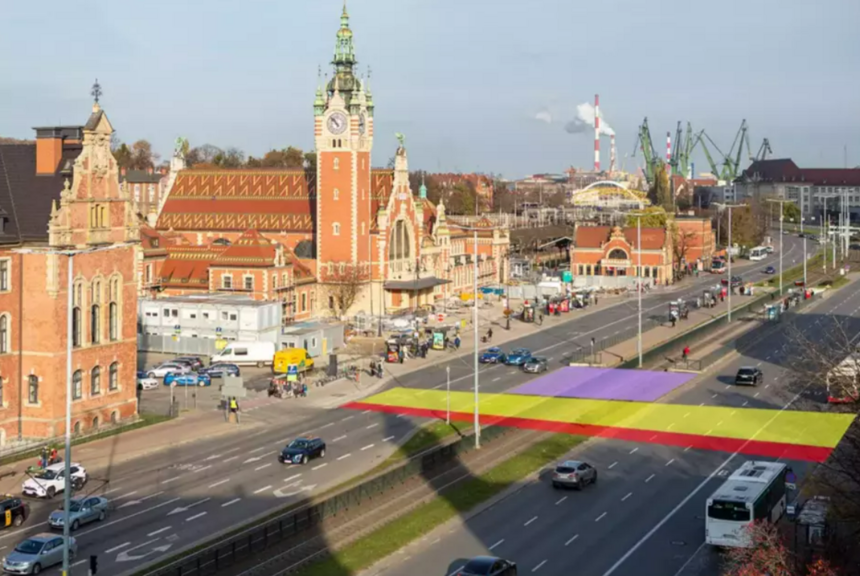 Wizualizacja przejścia naziemnego. Żółty kolor oznacza przejście dla pieszych, czerwony ścieżkę dla rowerzystów. Na fioletowo zaznaczono miejsce, gdzie rozbudowane zostaną istniejące przystanki tramwajowe, widać też fragment ulicy kilkupasmowej i zabytkowe budynki w tle