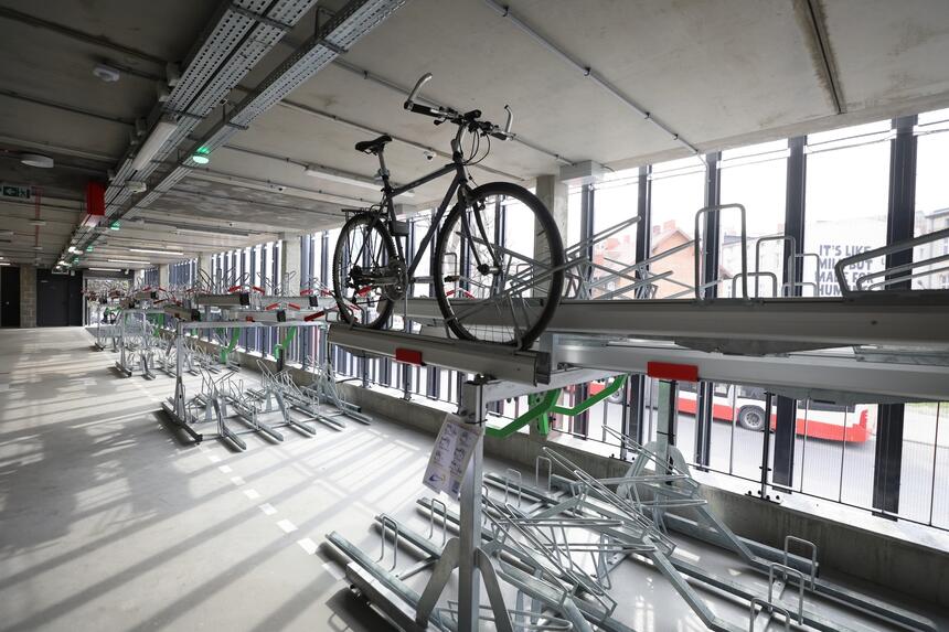 na zdjęciu kilkadziesiąt stojaków rowerowych wewnątrz budynku, na jednym z nich stoi rower
