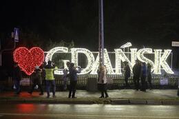 na zdjęciu wielka świąteczna iluminacja, to napis gdańsk i czerwone duże serce przed literką g, przed napisem stoi kilka osób, niektórzy robią zdjęcia napisowi
