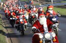 na zdjęciu parada motocyklistów przebranych w stroje mikołajów, na pierwszym planie mężczyzna w pełnym biało czerwonym stroju, z długą białą brodą, jedzie na motocyklu z szeroką kierownicą