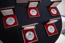 Pięć medali w okolicznościowych pudełkach na stole z granatowym obrusem
