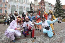 wolontariusze w przebraniach klaunów z puszkami pozują do zdjęcia na tle zabytkowego Gdańska, w tle Fontanna Neptuna