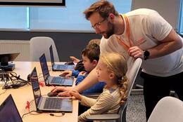 dzieci przy komputerach, obok nich instruktor