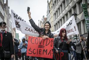 na czele marszu kobieta w skórzanej kurtce z czerwonym transparentem z napisem: Covid to ściema