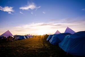 Harcerskie namioty na polu przy zachodzącym słońcu