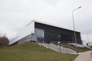 Widok nowoczesnej hali sportowej, która znajduje się na wzniesieniu, po lewej stronie zdjęcia. Prowadzą do niej schody
