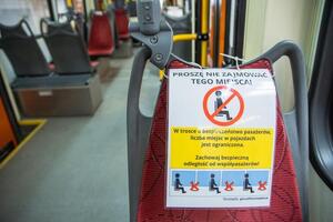 zdjęcie z pustego tramwaju, na czerwonym krzesełku kartka z napisem "Proszę nie zajmować tego miejsca" i przekreślonym ludzikiem