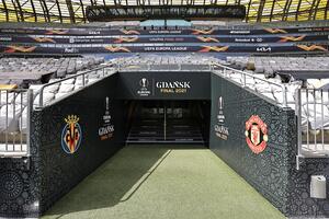 Fragment stadionu: wyjście z szatni, po bokach loga zespołów Villarreal i Manchesteru United. Wyżej trybuny z krzesełkami 