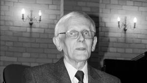 Czarno-białe zdjęcie: popiersie starszego mężczyzny w garniturze i okularach