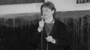 Czarno-białe zdjęcie: kobieta w średnim wieku stoi przed mikrofonem