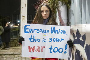 dziewczyna trzyma nocą transparent z napisem "European Union This is Your War Too"