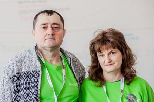 mężczyzna i kobieta w średnim wieku pozują przytuleni do zdjęcia, mają na sobie zielone t-shirty wolontariuszy
