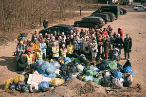 to grupowe pamiątkowe zdjęcie, pozuje grupa około czterdziestu osób, przed nimi leży kilkadziesiąt dużych worków wypełnionych śmieciami