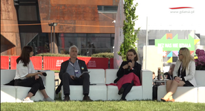 na zdjęciu cztery osoby siedzą na białej szerokiej kanapie, w tle widać rdzawą elewację budynku europejskiego centrum solidarności