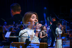 Zdjęcie z koncertu w Filharmonii Bałtyckiej wokalistka na tle orkiestry i dyrygenta.
