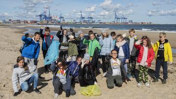 Uśmiechnięta grupa kilkudziesięciu dzieci na plaży machająca rękoma