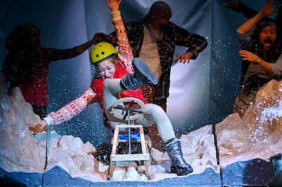 aktorka w stroju zimowym na sankach na scenie