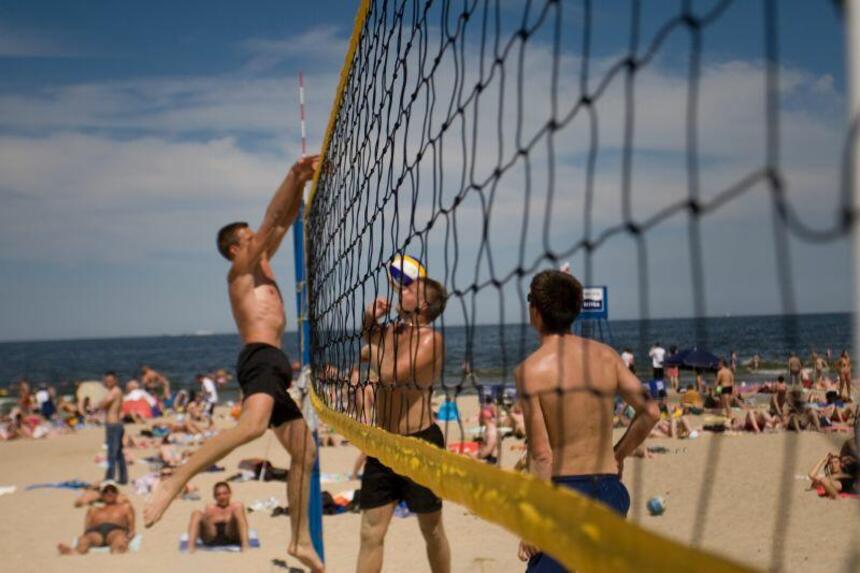 walka siatkarzy na plaży latem, akcja zawodnika z piłką pod siatką 