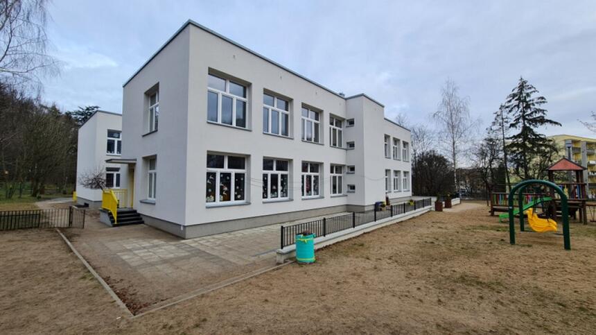 na zdjęciu dwupoziomowy budynek przedszkola, o jasnej elewacji z licznymi oknami