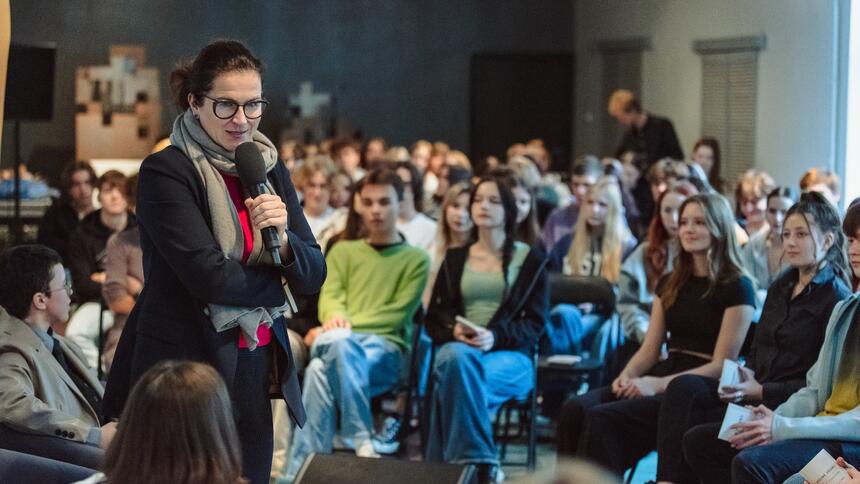 Kobieta w średnim wieku w okularach mówiąca do uczniów 