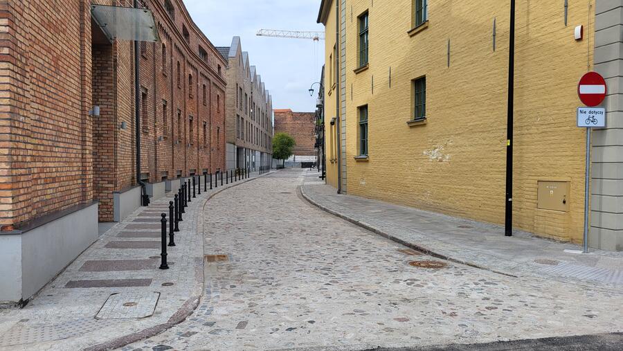 na zdjęciu fragment brukowanej ulicy, po obu jest stronach fragmenty kamienic