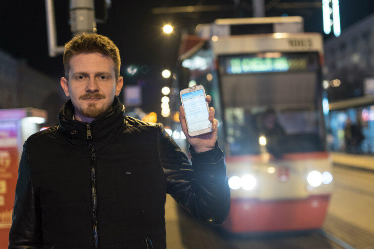 Jarek Szmigielski z telefonem wyposażonym w „Zdążusia” czeka na swój tramwaj.
