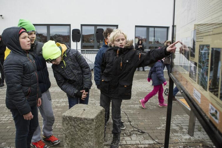 Historia i współczesność: dzieci ze szkoły w Kokoszach stoją wokół słupa granicznego z Wolnego Miasta Gdańska i czytają tablicę o historii naszego miasta.