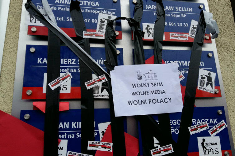 Znajdujące się na ścianie budynku tablice z nazwiskami parlamentarzystów PiS zostały pozaklejane czarną taśmą i nalepkami z hasłami opozycji