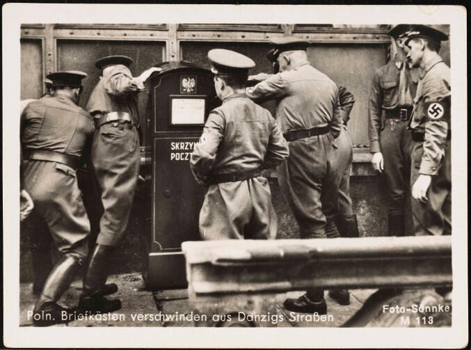 Fotografia czarno-biała ukazuje usuwanie polskich skrzynek pocztowych z ulic w Gdańsku przez oddziały niemieckie