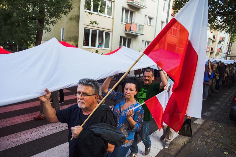 Przemarsz zwolenników KODu z ogromną flagą Polski