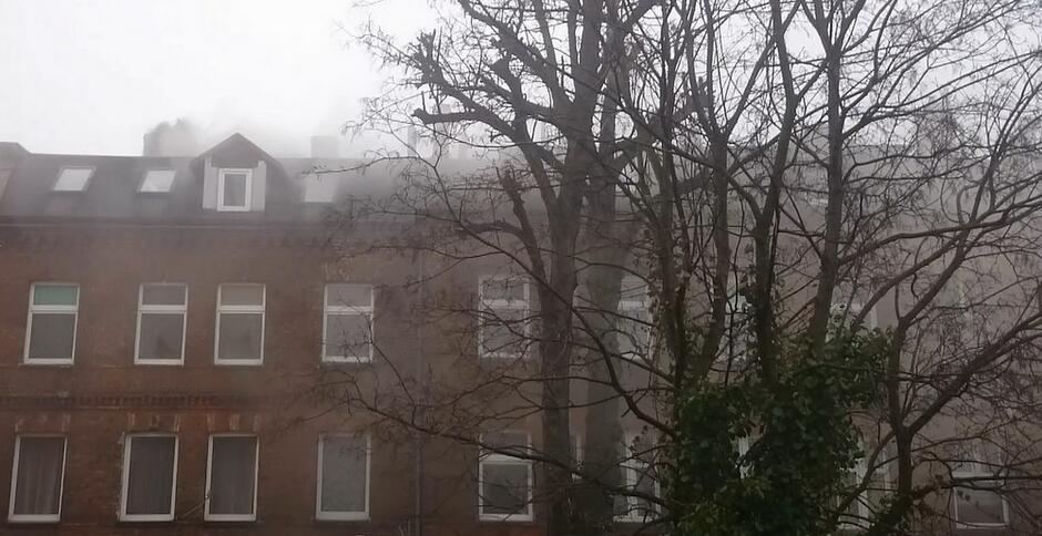 Budynek zasnuty kłębami dymu wydobywającymi się z kominów z jego kominów.