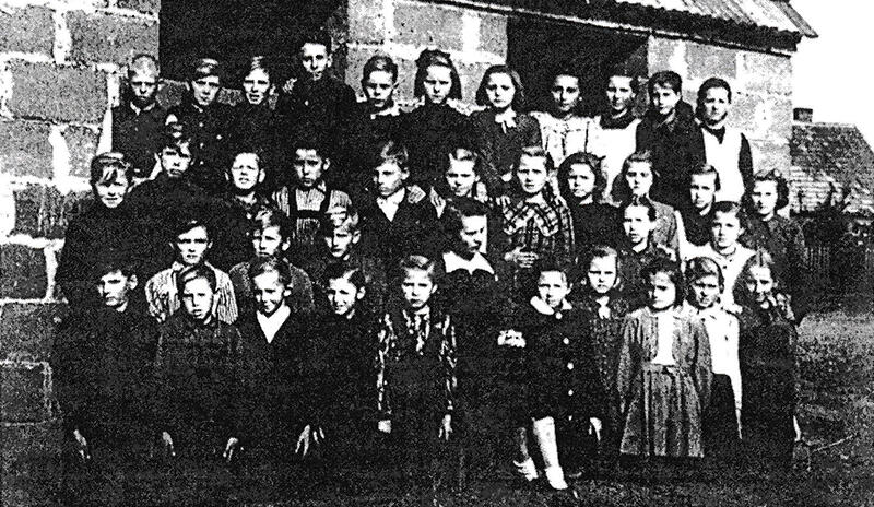 Pierwsi uczniowie nowo wybudowanej szkoły na tle budynku gospodarczego - 1948 r.