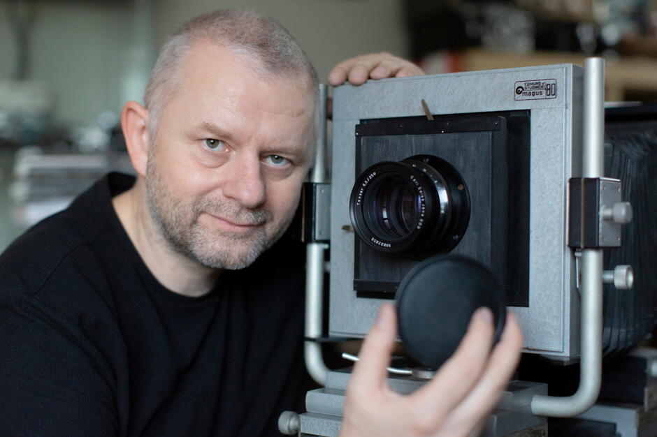 Grzegorz Mehring - fotoreporter i pasjonat starych polskich aparatów fotograficznych. Pozuje ze swoim Magusem 80, aparatem studyjnym z manufaktury Edmunda Studnickiego