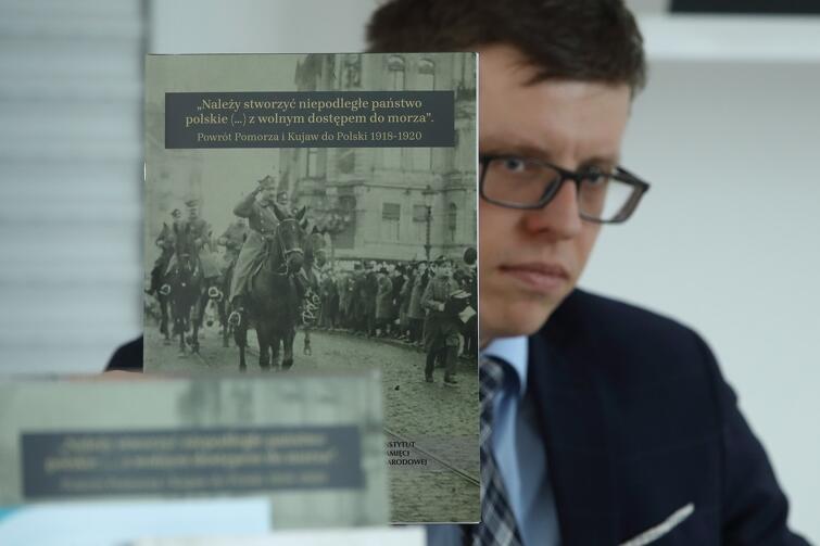 Krzysztof Drażba, naczelnik Oddziałowego Biura Edukacji Narodowej IPN w Gdańsku, prezentuje wydawnictwo o okolicznościach, w jakich Kujawy i Pomorze wróciły do Polski w latach 1918-1920