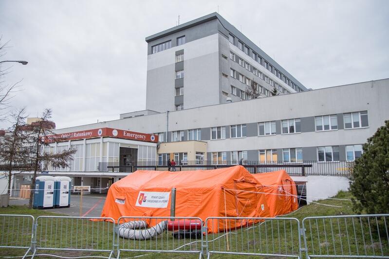 Budynek szpitala, przed nim dwa pomarańczowe namioty, obok dwie toalety toi toi