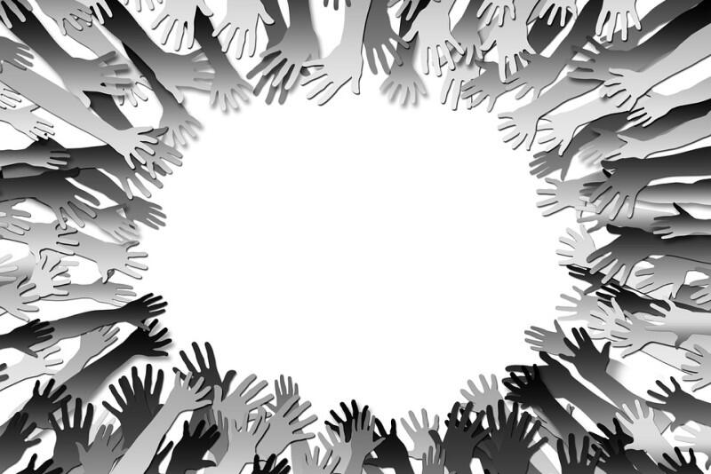 Symboliczna ilustracja, która przedstawia wewnętrzną stronę dłoni wielu osób o różnych kolorach skóry. Ręce przedstawione są w geście oznaczającym potrzebę pomocy. Jest ich wiele, ułożone są koliście, jedna obok drugiej