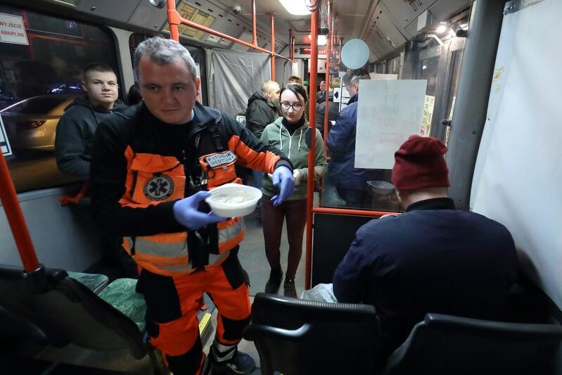 Wnętrze gdańskiego autobusu S.O.S. - na pierwszym planie ratownik medyczny z talerzem gorącej zupy, wokół kilka osób korzystających z pomocy