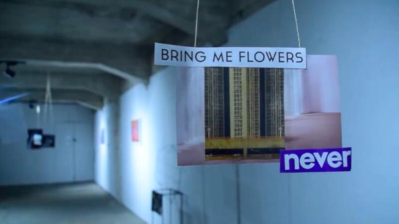 Korytarz w budynku, wiszące zdjęćie bloku z napisem: bring me flowers never.
