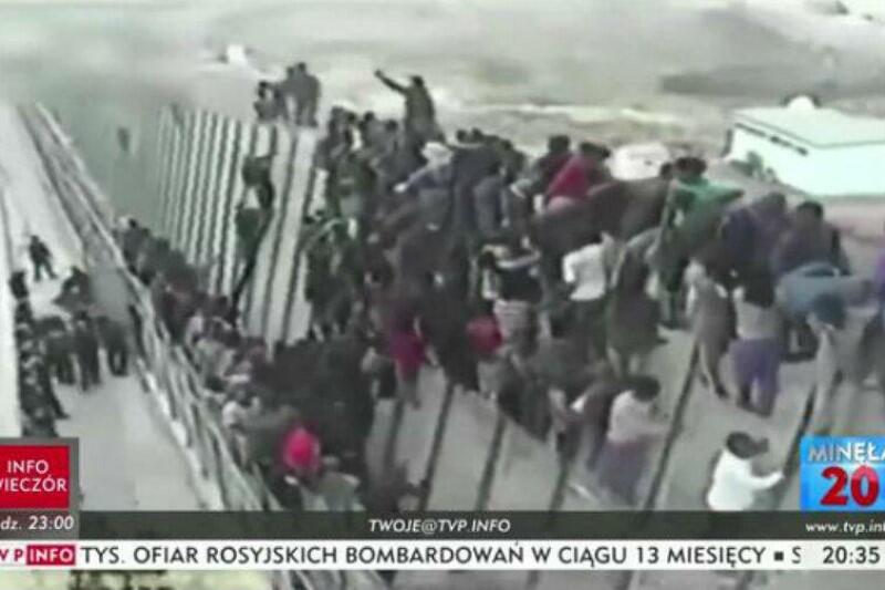 Kadr z filmu przedstawia tłum imigrantów forsujących mur na granicy jednego z państw europejskich