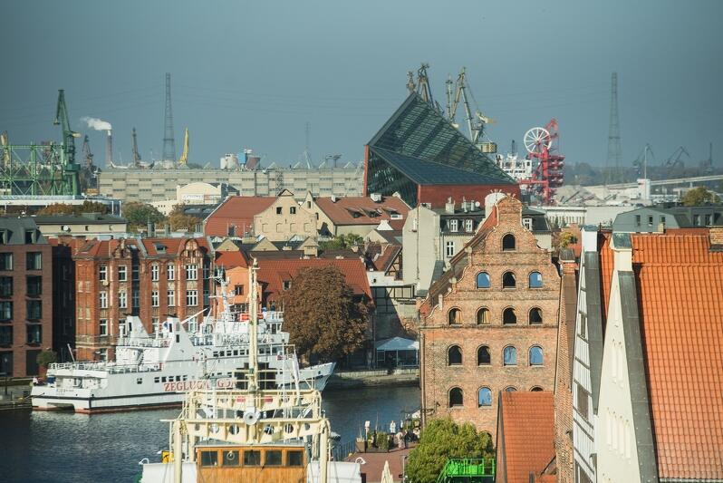 Fragment Gdańska nad Motławą, w tle wybija się Muzeum II Wojny Światowej, dalej stoczniowe żurawie 