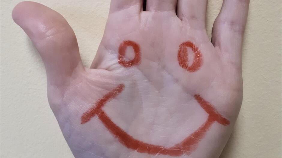 Znak uśmiechniętej buźki wymalowany flamastrem na dłoni